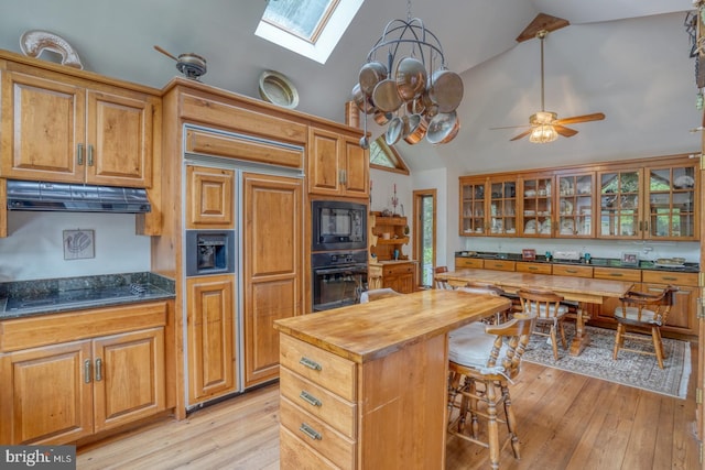 kitchen featuring a skylight, light hardwood / wood-style flooring, ceiling fan, and black appliances