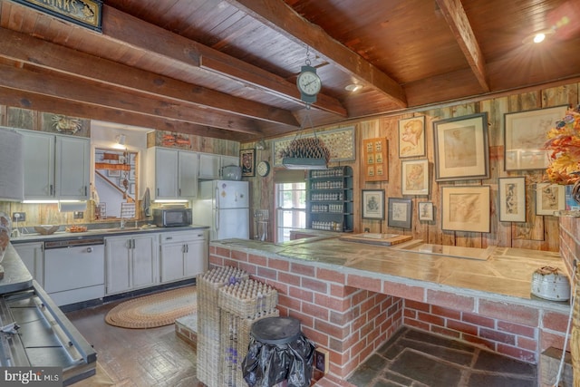 kitchen with gray cabinetry, white appliances, dark wood-type flooring, beamed ceiling, and kitchen peninsula