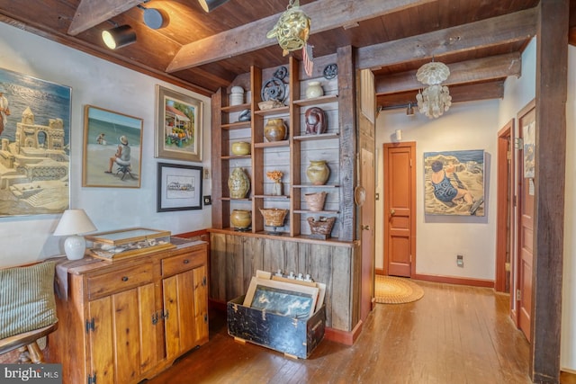 hallway with lofted ceiling with beams, light hardwood / wood-style floors, and wood ceiling