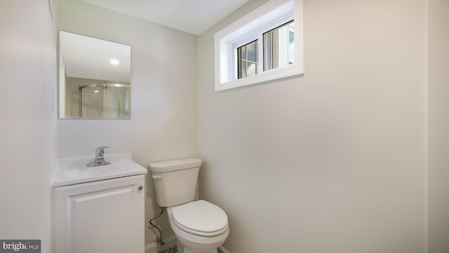 bathroom featuring a shower with shower door, toilet, and vanity