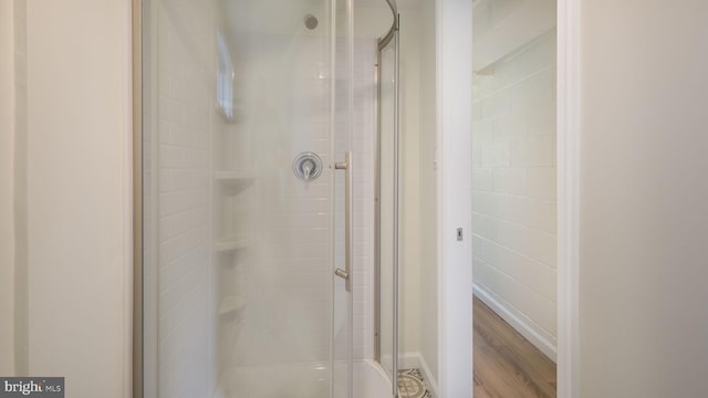 bathroom with a shower with door and hardwood / wood-style floors