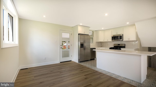 kitchen featuring tasteful backsplash, hardwood / wood-style floors, stainless steel appliances, and white cabinets