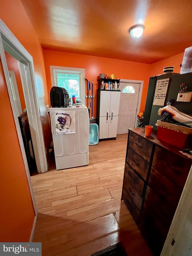 clothes washing area with light hardwood / wood-style flooring and washer / dryer