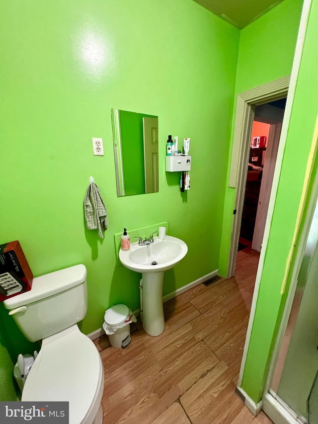 bathroom featuring hardwood / wood-style floors, toilet, and an enclosed shower