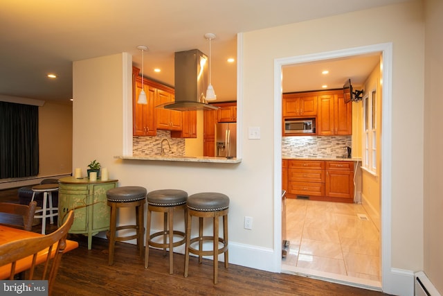 kitchen with light hardwood / wood-style flooring, baseboard heating, tasteful backsplash, island range hood, and appliances with stainless steel finishes