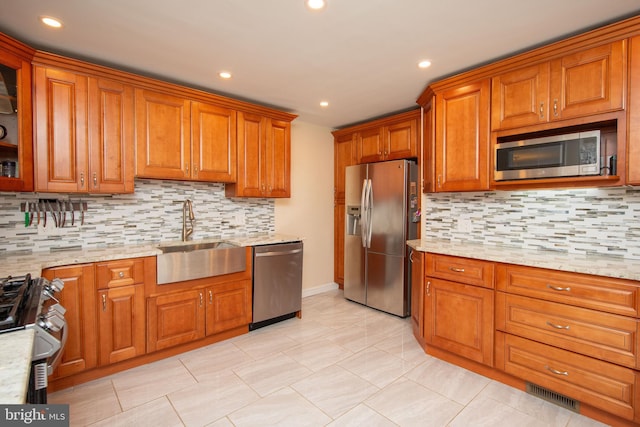 kitchen featuring backsplash, sink, light stone counters, light tile patterned floors, and stainless steel appliances