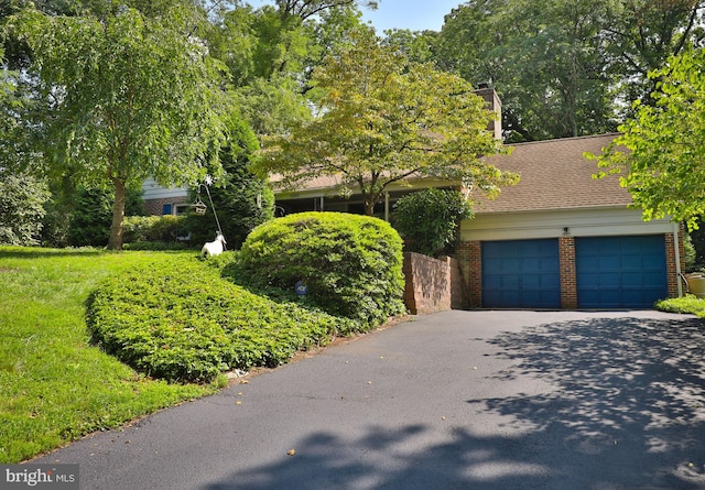 obstructed view of property featuring a garage and a front yard