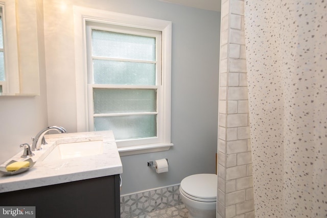 bathroom with toilet, vanity, and tile patterned floors