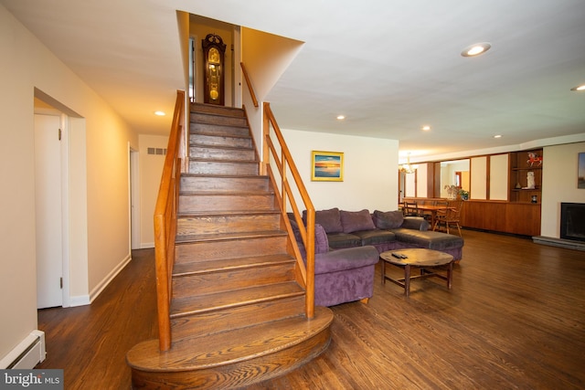 staircase with a baseboard heating unit and hardwood / wood-style flooring