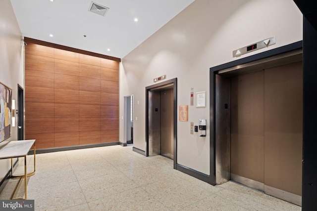 hallway with elevator and a towering ceiling