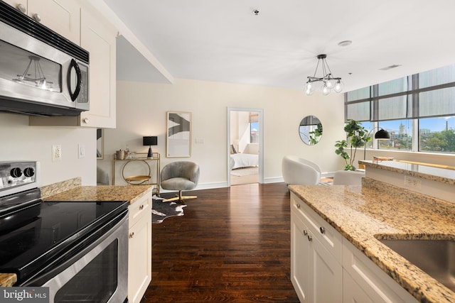 kitchen featuring stainless steel appliances, dark wood-type flooring, white cabinetry, and light stone counters