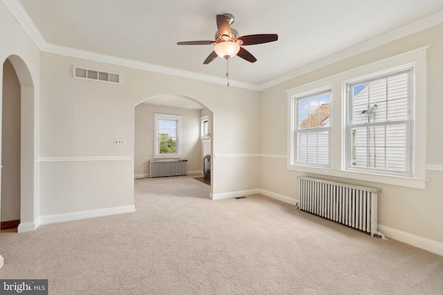 carpeted empty room with radiator heating unit, ceiling fan, and a healthy amount of sunlight