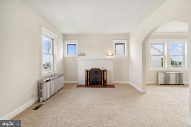 living room with radiator, light colored carpet, and plenty of natural light