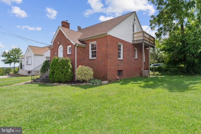 view of side of home featuring a balcony, a chimney, a lawn, and brick siding