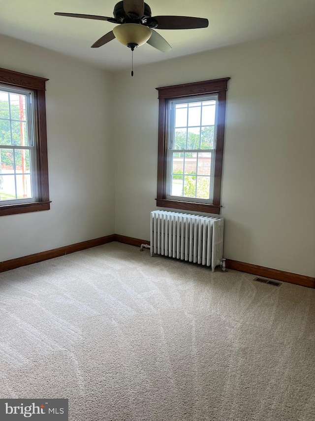 unfurnished room with carpet floors, ceiling fan, and radiator heating unit