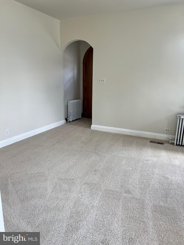 empty room with light colored carpet and radiator heating unit