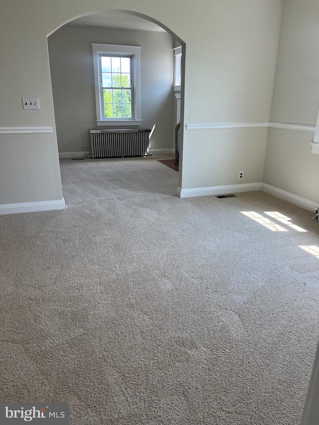 carpeted empty room featuring radiator heating unit