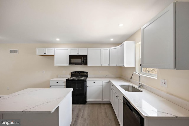 kitchen featuring white cabinetry, light hardwood / wood-style floors, light stone countertops, sink, and black appliances