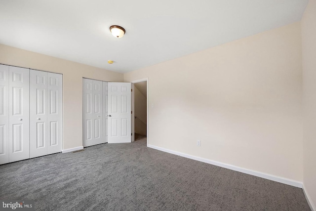unfurnished bedroom featuring carpet floors and multiple closets