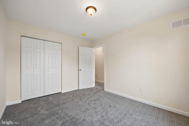 unfurnished bedroom with dark carpet and a closet