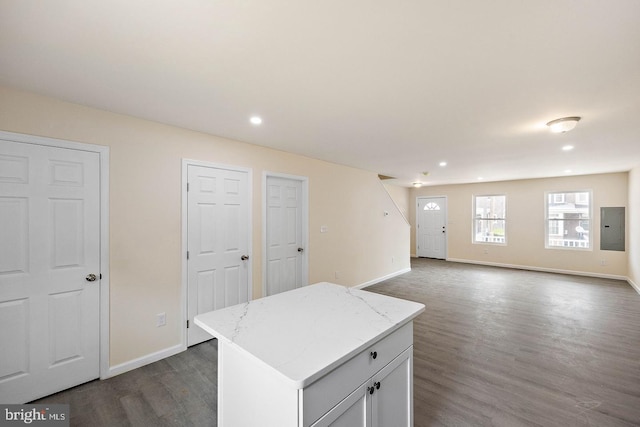 kitchen featuring white cabinetry, a center island, electric panel, light stone counters, and dark wood-type flooring