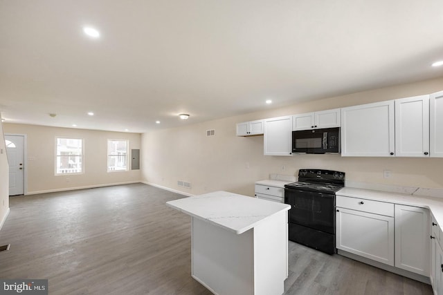 kitchen featuring light hardwood / wood-style flooring, white cabinetry, light stone counters, black appliances, and a center island