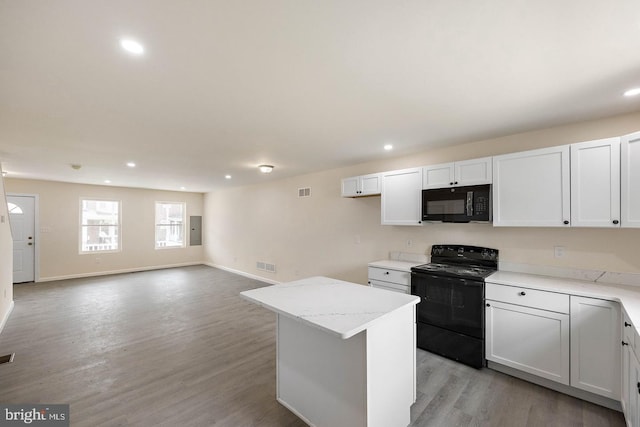 kitchen featuring white cabinetry, light stone counters, light wood-type flooring, a kitchen island, and black appliances