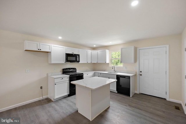 kitchen with sink, a kitchen island, white cabinetry, hardwood / wood-style flooring, and black appliances