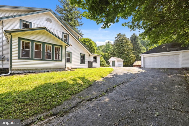 view of side of home with a garage, an outbuilding, and a lawn