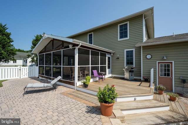 back of house featuring a wooden deck, a patio area, and a sunroom