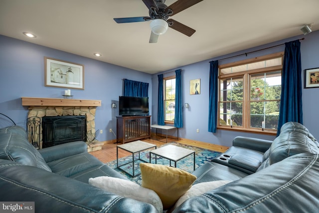 living room featuring hardwood / wood-style floors, a stone fireplace, and ceiling fan