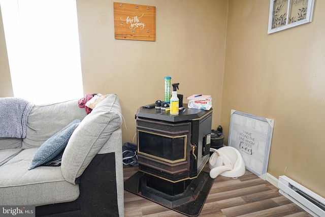 bedroom featuring hardwood / wood-style flooring, a wood stove, and a baseboard radiator