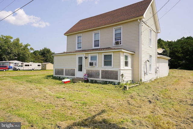 rear view of house with cooling unit and a lawn