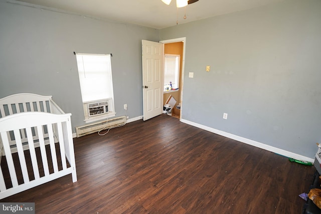 unfurnished bedroom with hardwood / wood-style floors, a crib, and a baseboard radiator