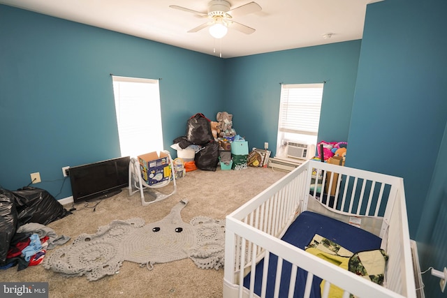 bedroom featuring ceiling fan, a crib, and carpet