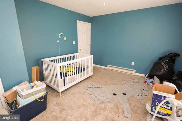 bedroom with a crib, carpet floors, and a baseboard radiator