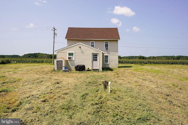 back of property featuring a storage unit and a lawn