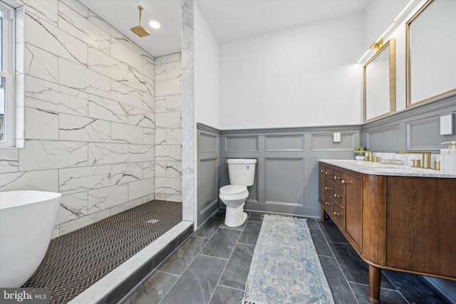 full bathroom with vanity, tiled shower, a freestanding tub, a decorative wall, and toilet