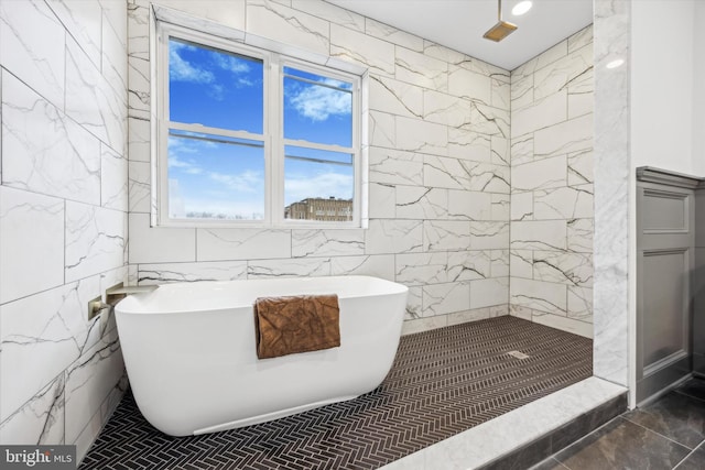 full bathroom featuring a tile shower, a freestanding bath, and tile walls