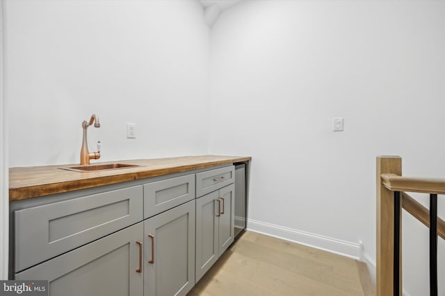 interior space featuring baseboards, light wood-style floors, and a sink