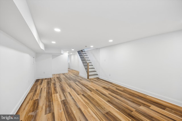 finished basement with stairway, recessed lighting, wood finished floors, and baseboards