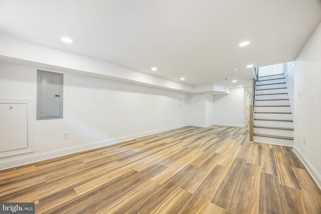 basement with light wood-type flooring and electric panel