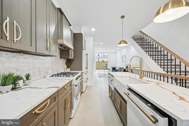 kitchen with light wood-style floors, white gas range oven, pendant lighting, wall chimney exhaust hood, and backsplash