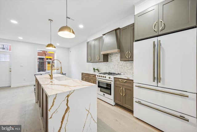 kitchen featuring visible vents, a sink, white appliances, wall chimney exhaust hood, and decorative backsplash