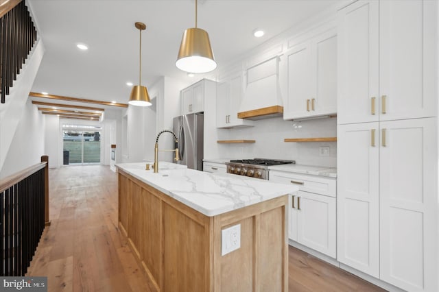 kitchen with white cabinetry, stainless steel appliances, decorative light fixtures, and light hardwood / wood-style floors