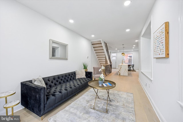 living area featuring recessed lighting, baseboards, stairs, and light wood finished floors