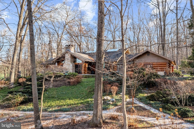 view of front facade with log siding, metal roof, and a chimney