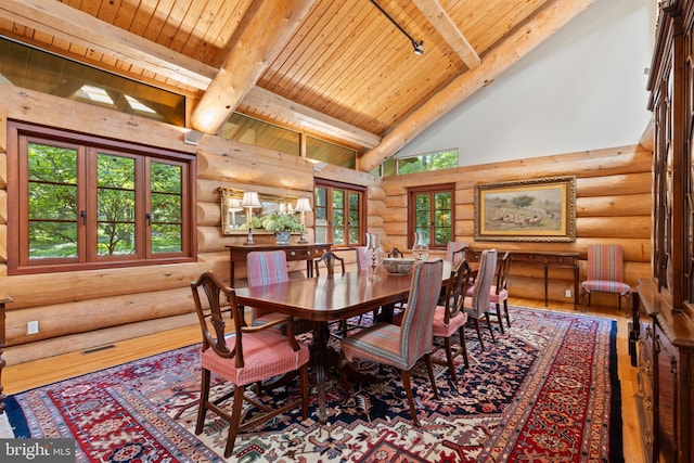 dining room featuring rustic walls, hardwood / wood-style floors, beamed ceiling, high vaulted ceiling, and wood ceiling