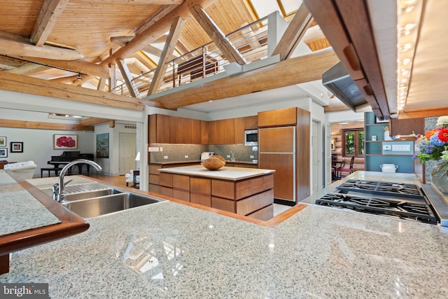 kitchen featuring built in appliances, brown cabinetry, beamed ceiling, decorative backsplash, and a sink