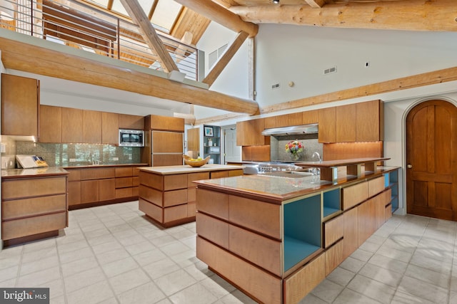 kitchen featuring tasteful backsplash, a center island, built in appliances, under cabinet range hood, and high vaulted ceiling